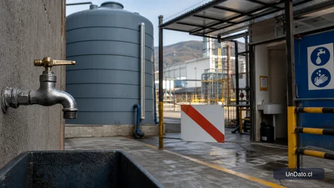 Llave de agua, estanque de respaldo y aviso de suspensión en la entrada de un lugar de trabajo afectado por un corte de suministro.